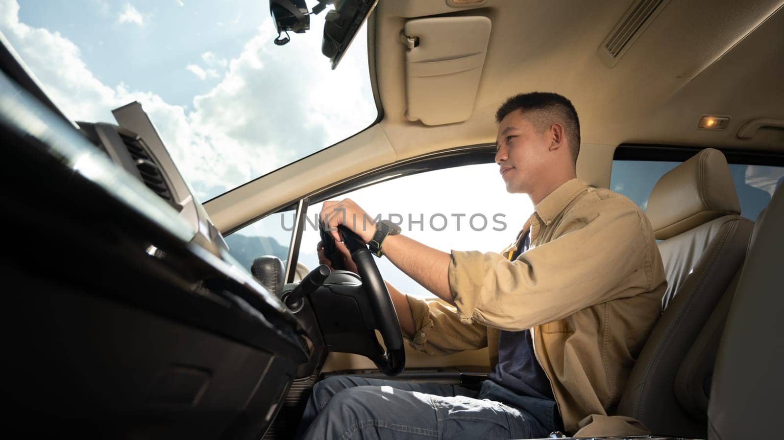 Handsome man driving car enjoying road trip on vacation. Transport, summer vacation and holiday by prathanchorruangsak