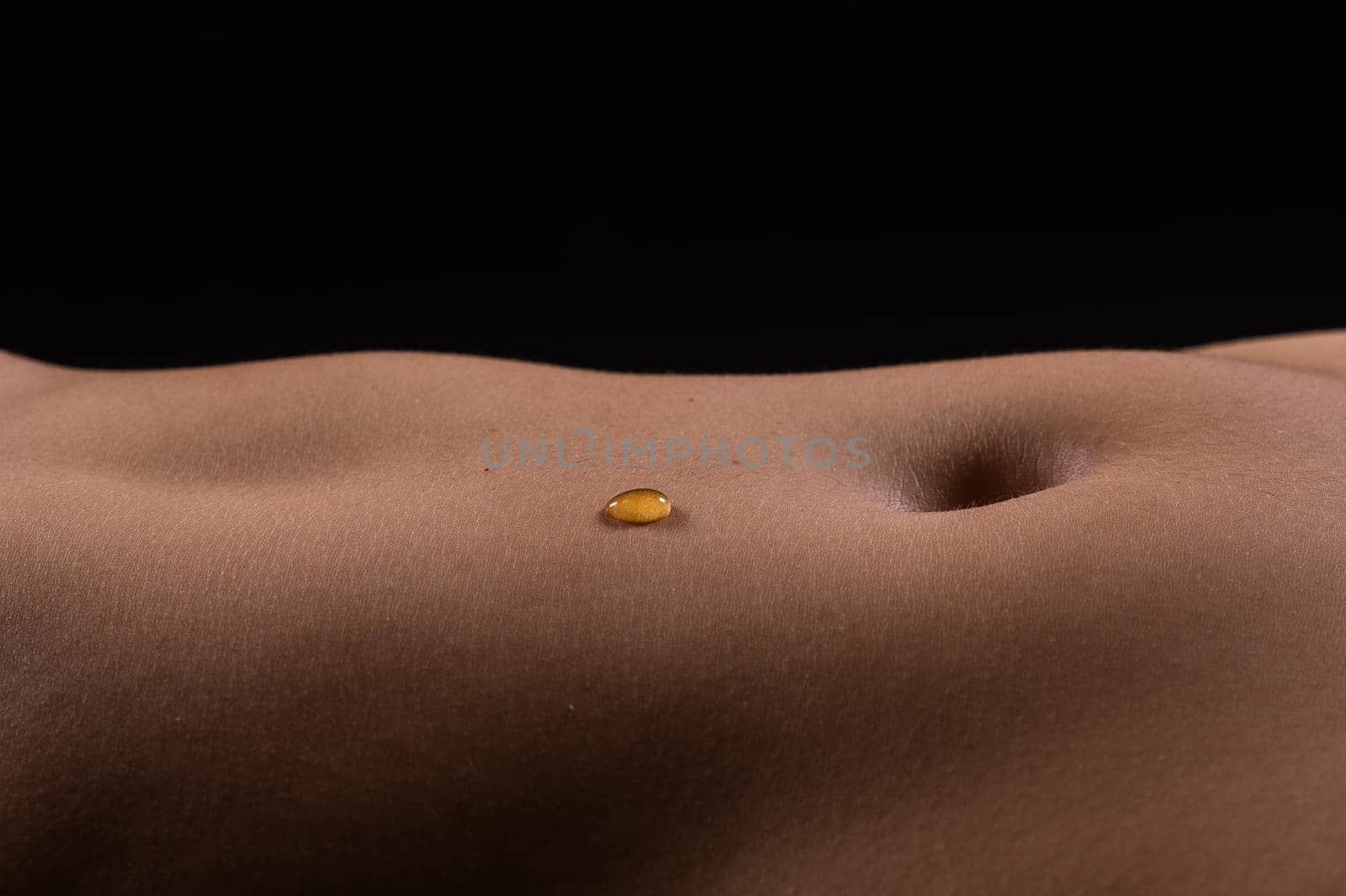 Beautiful female body in honey on a dark background, studio