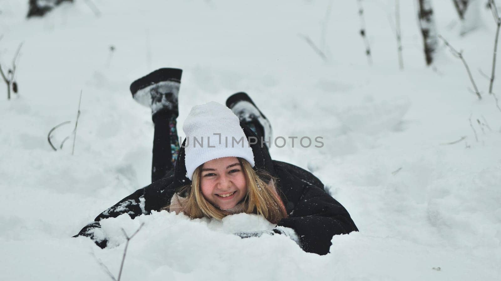 A girl falls on the snow in winter in the forest