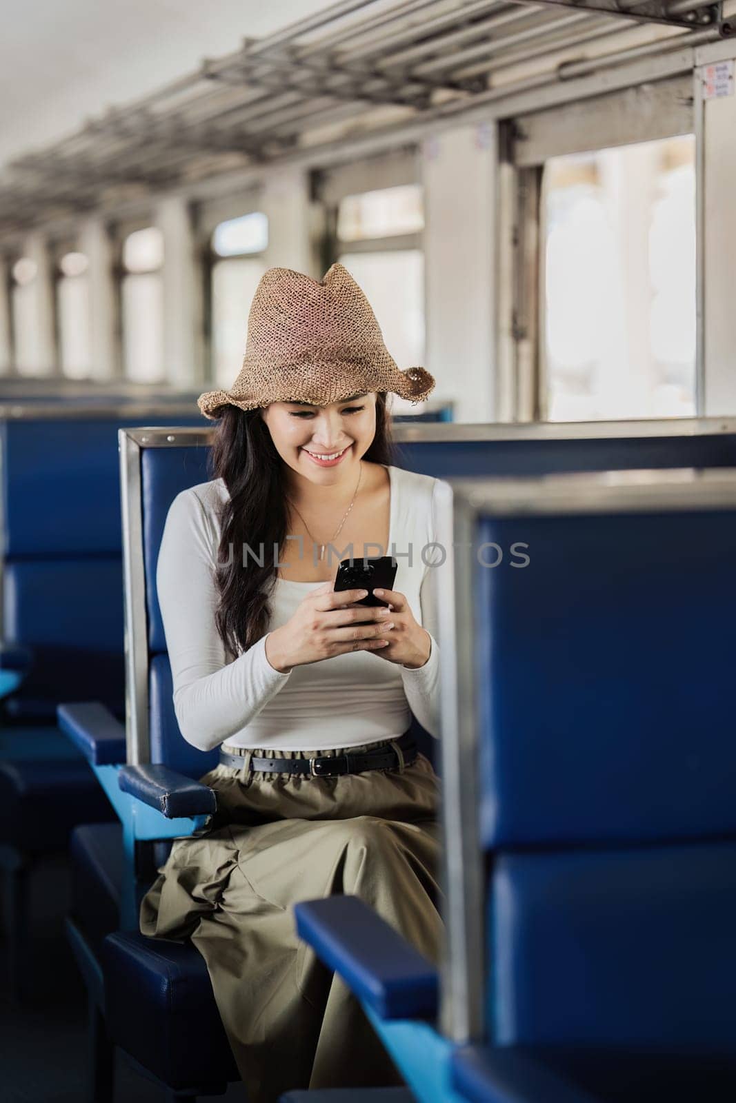 Happy young woman watching video holding mobile phone during transport on travel vacation.