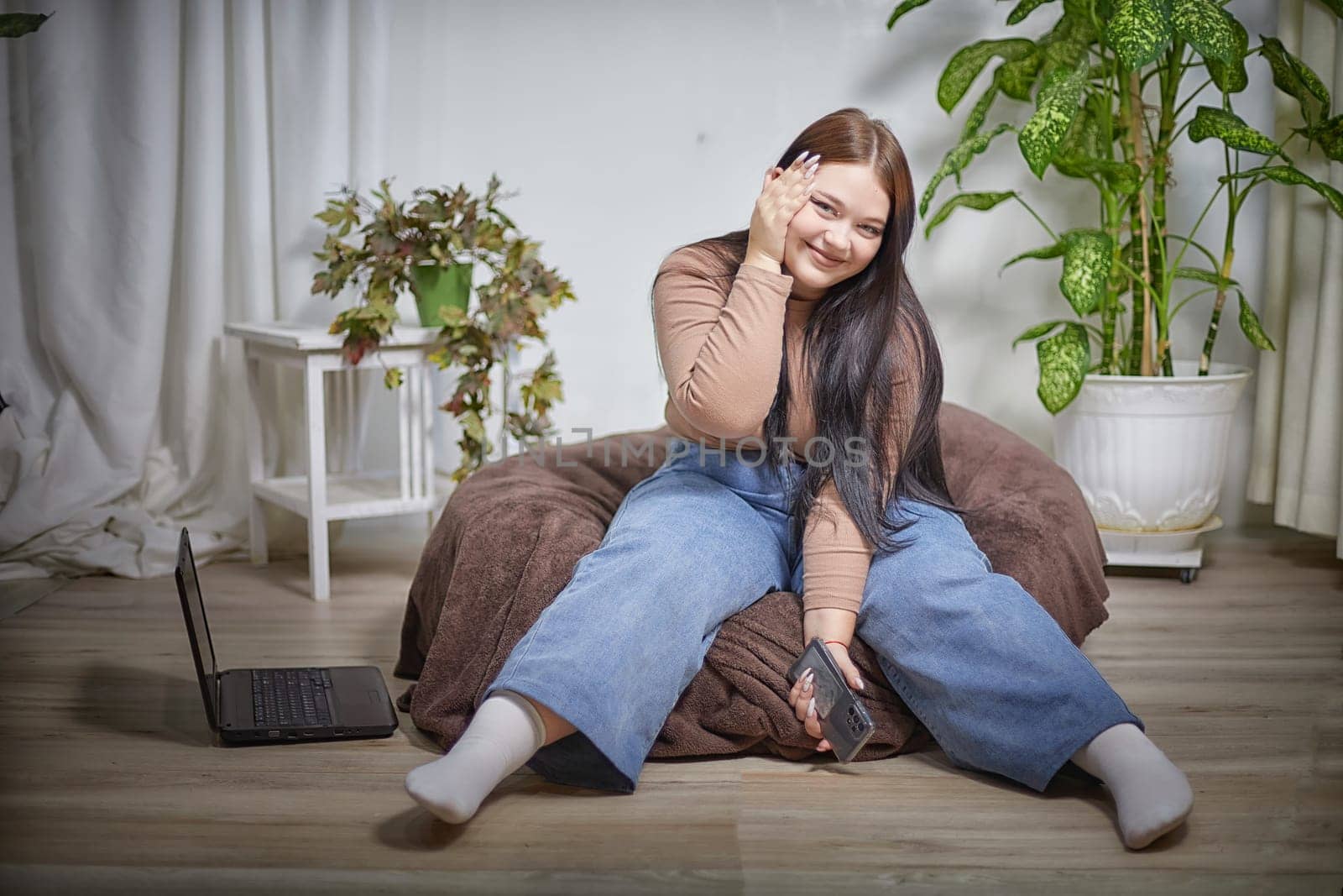 Stylish chubby student brunette girl with cell mobile phone. Attractive young brunette overweight indoors