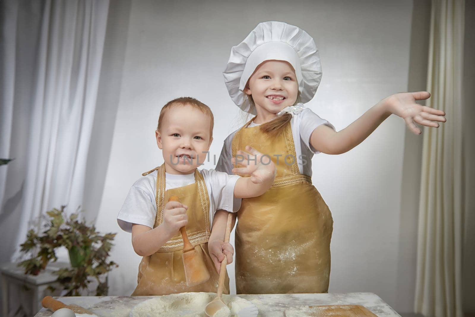 Cute oriental family with small brother and sister cooking in the kitchen on Ramadan, Kurban-Bairam, Eid al-Adha. Funny children boy and girl at cook photo shoot. Pancakes, Maslenitsa, Easter