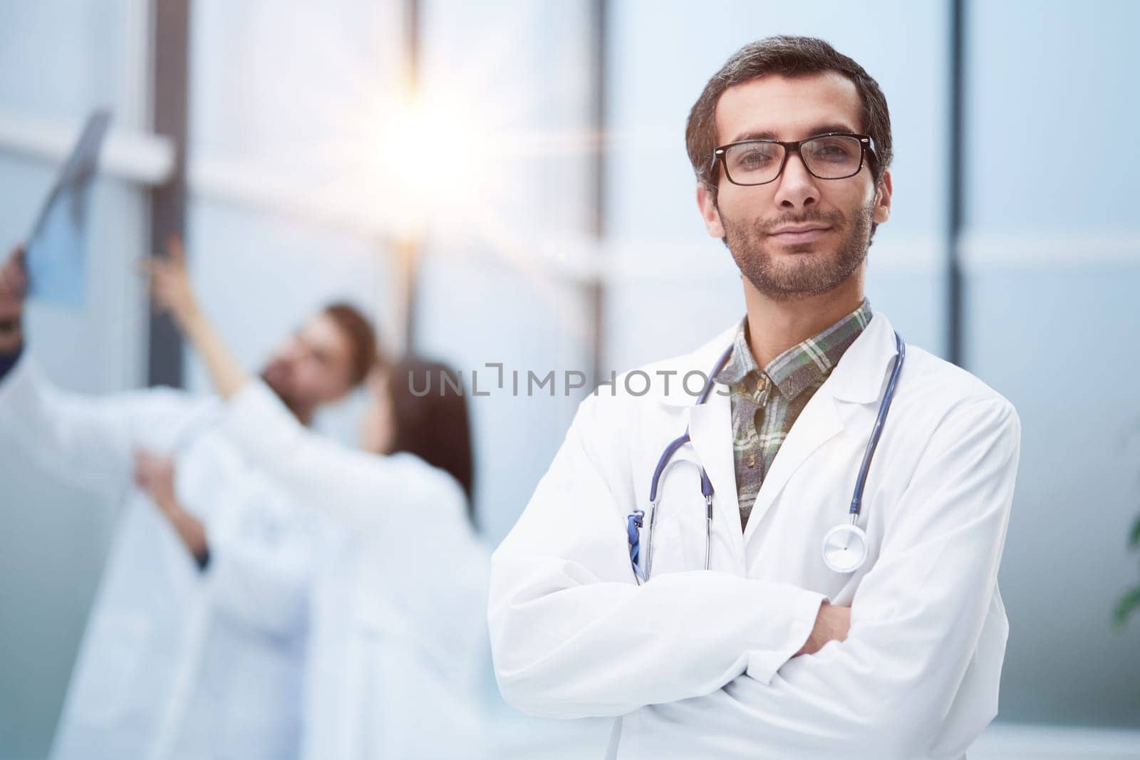 Confident doctor posing with arms crossed, he is smiling at camera by Prosto