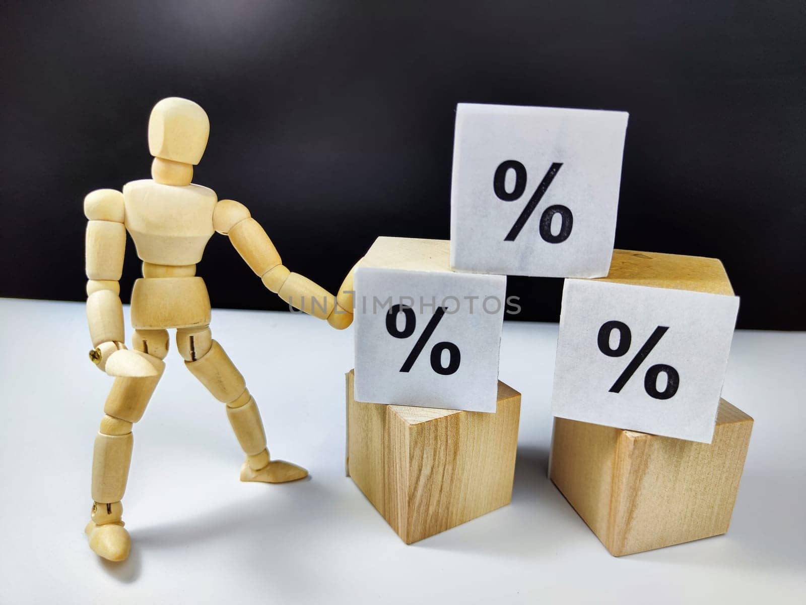 Little wooden man, cubes in a pyramid and growth arrows and percent signs. The concept of applying efforts that lead to results. Scammers offering huge profits without difficulty