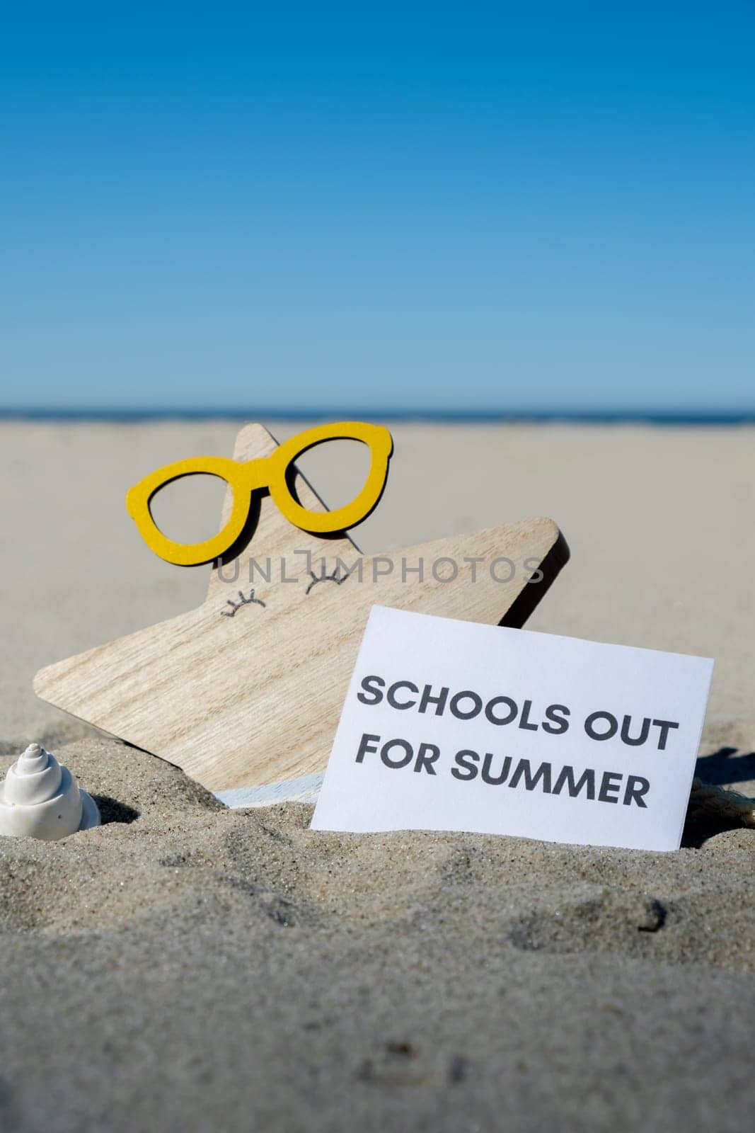 SCHOOLS OUT FOR SUMMER text on paper greeting card on background of funny starfish in glasses summer vacation decor. Sandy beach sun coast. Holiday concept postcard. Getting away Travel Business concept