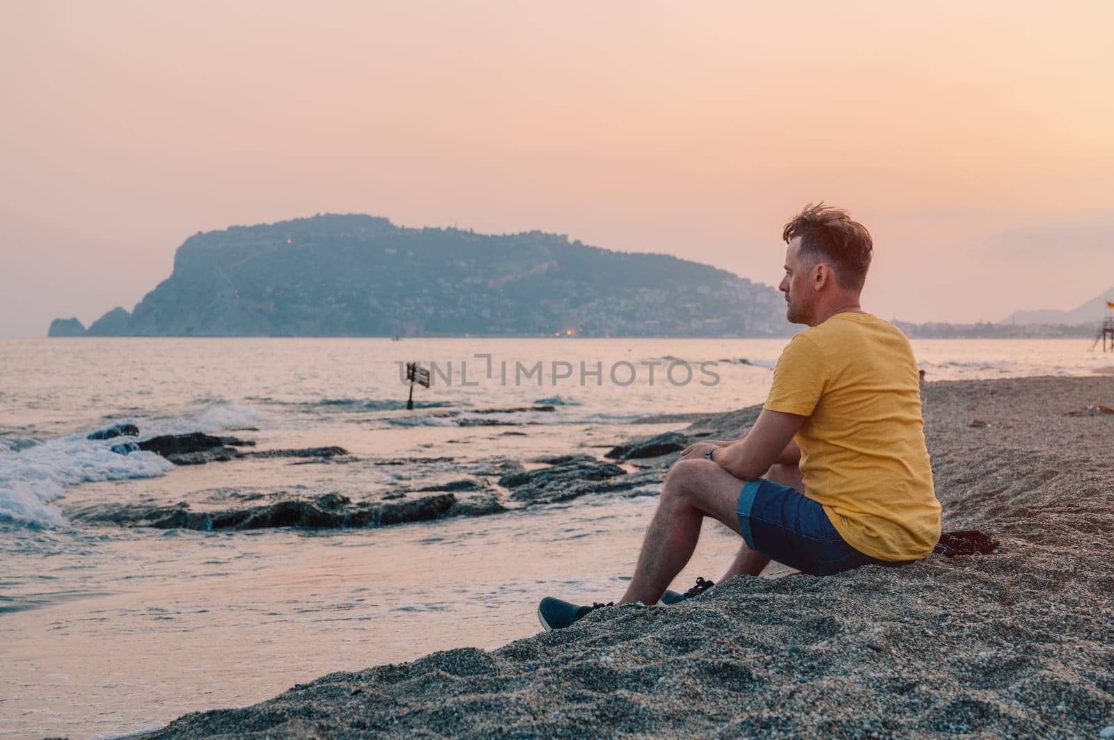Man sits on the beach and looks at the sea in Alanya city by rusak