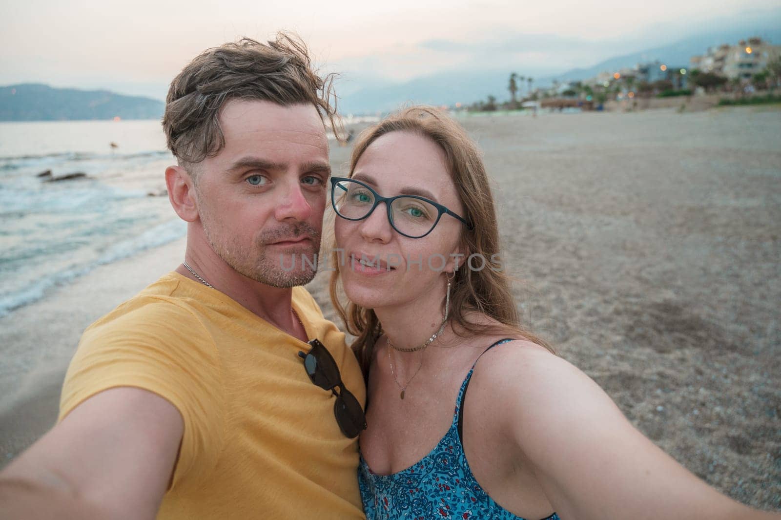 Happy couple taking a photo on a beach at the sea in Alanya city, Turkey. Travelling or vacation concept