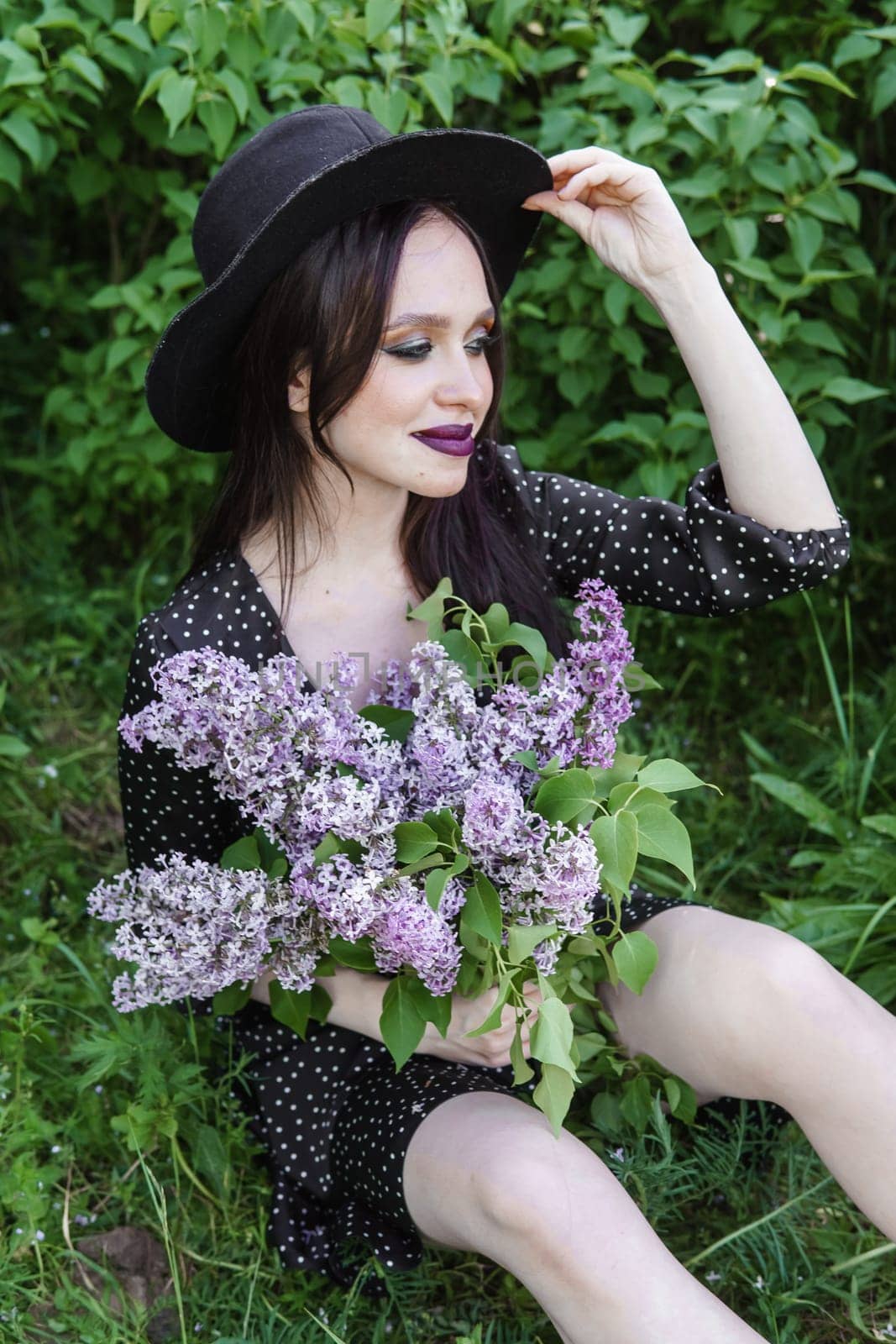 A fashionable girl with dark hair, a spring portrait in lilac tones in summer. Bright professional makeup