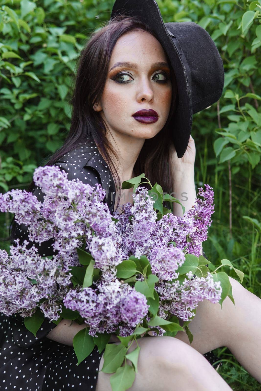 A fashionable girl with dark hair, a spring portrait in lilac tones in summer. Bright professional makeup