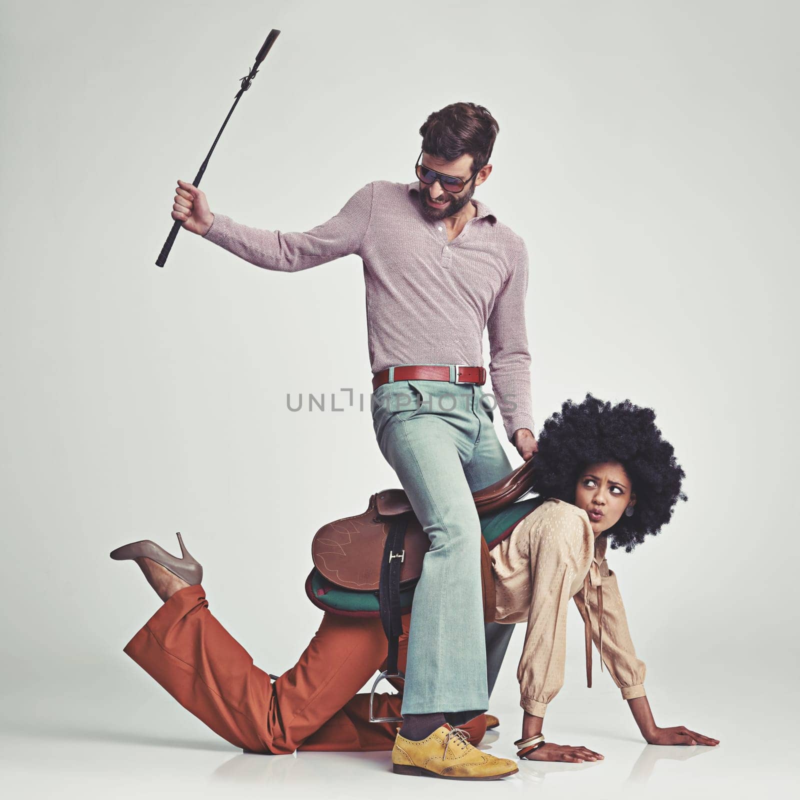 Retro, man and woman or riding crop in studio with piggyback, portrait and funny face for vintage style. Friends, people and 70s outfit with hipster clothes or comic expression with white background.