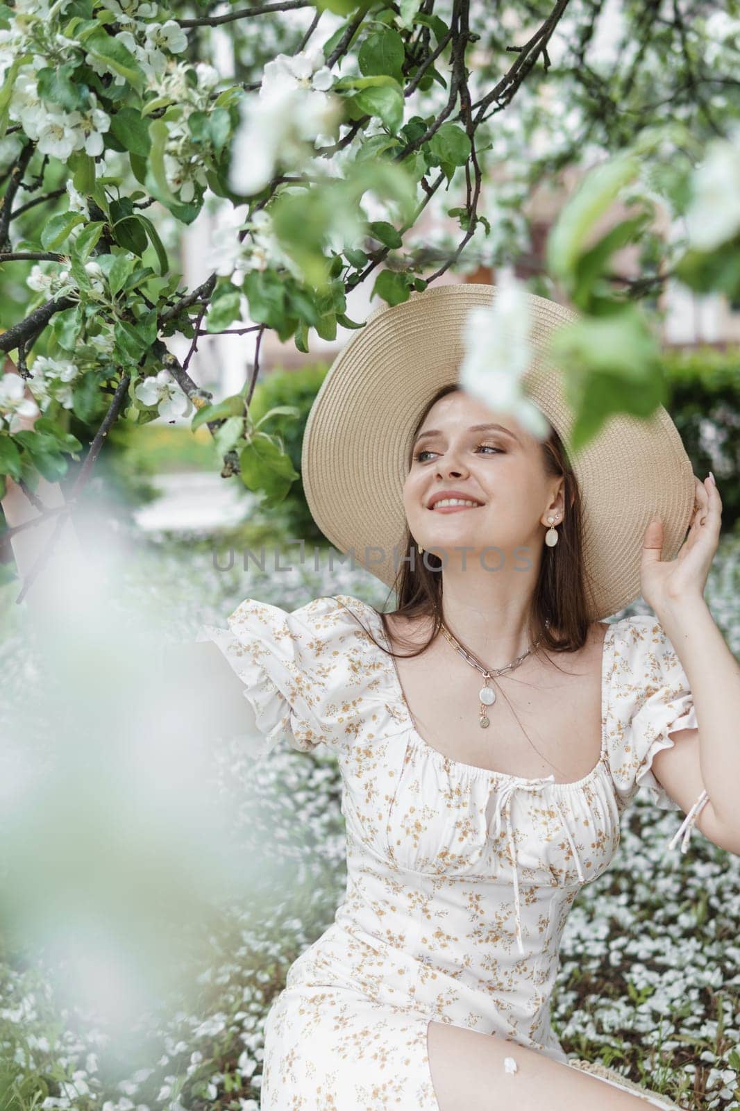 An attractive long-haired woman walks in the spring in the park of blooming apple trees. Spring portrait of a woman