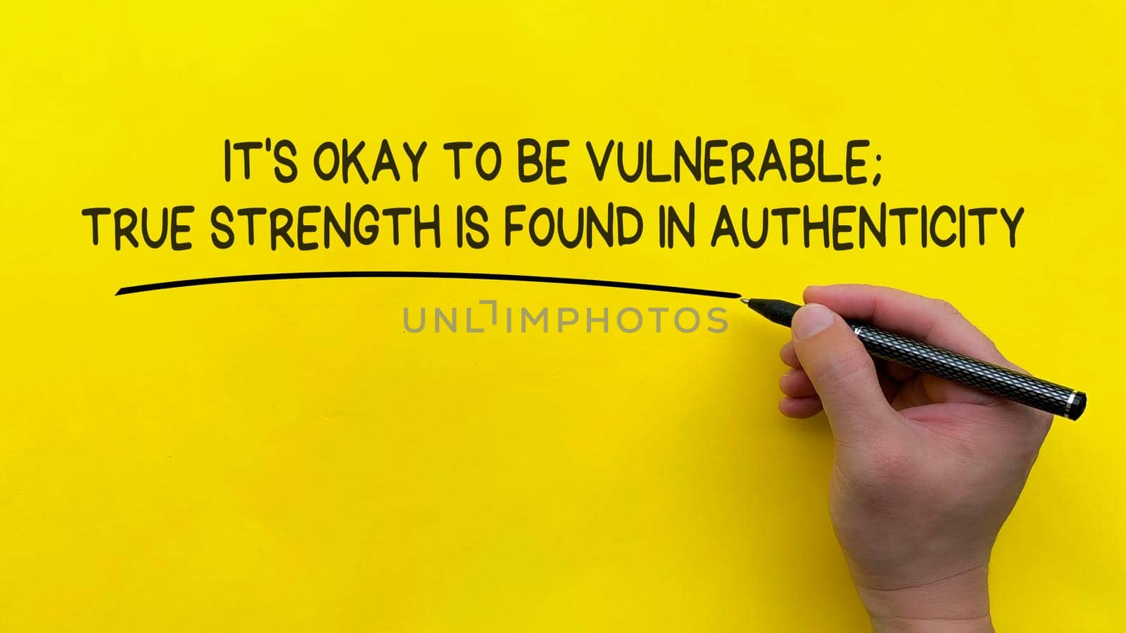 Hand writing It is okay to be vulnerable affirmation on yellow cover background. Affirmation concept