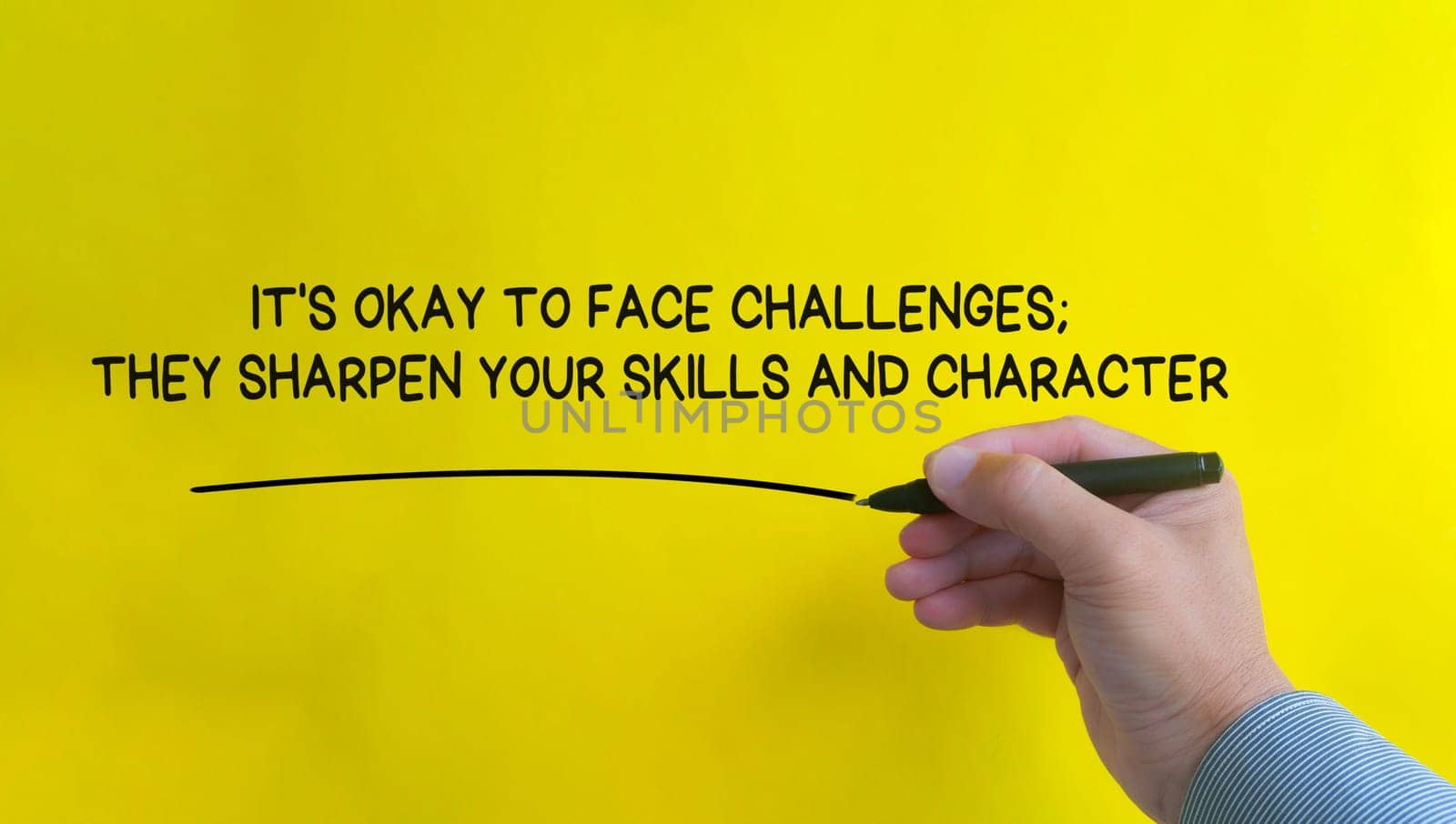 Hand writing It is okay to face challenges affirmation on yellow cover background. Affirmation concept