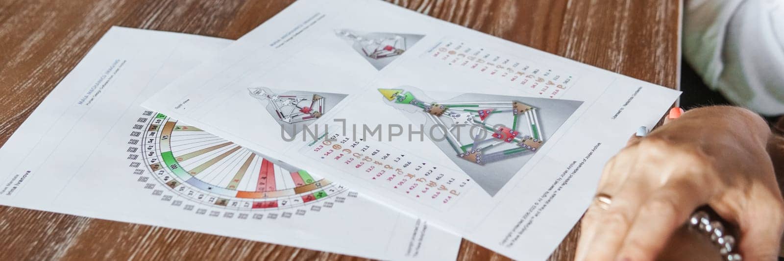 Tver, Russia - August 2, 2021. A woman in a cafe at a table is studying the design of a person. The concept of studying esoteric sciences. A bodigraph or a map of a person on an A4 sheet.