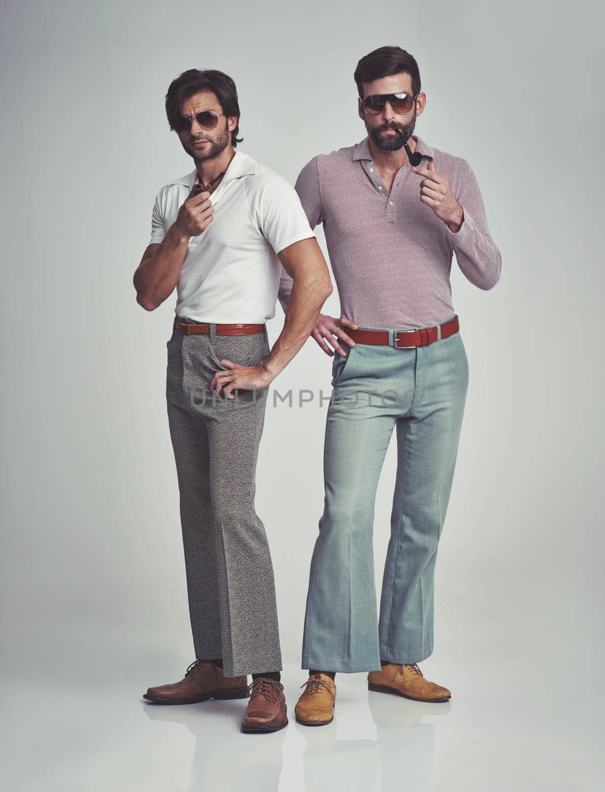 Vintage, men and sunglasses or pipe in studio with fashion model, hipster outfit or confidence with calm expression. Friends, people and attitude with 70s style or retro clothes with white background by YuriArcurs