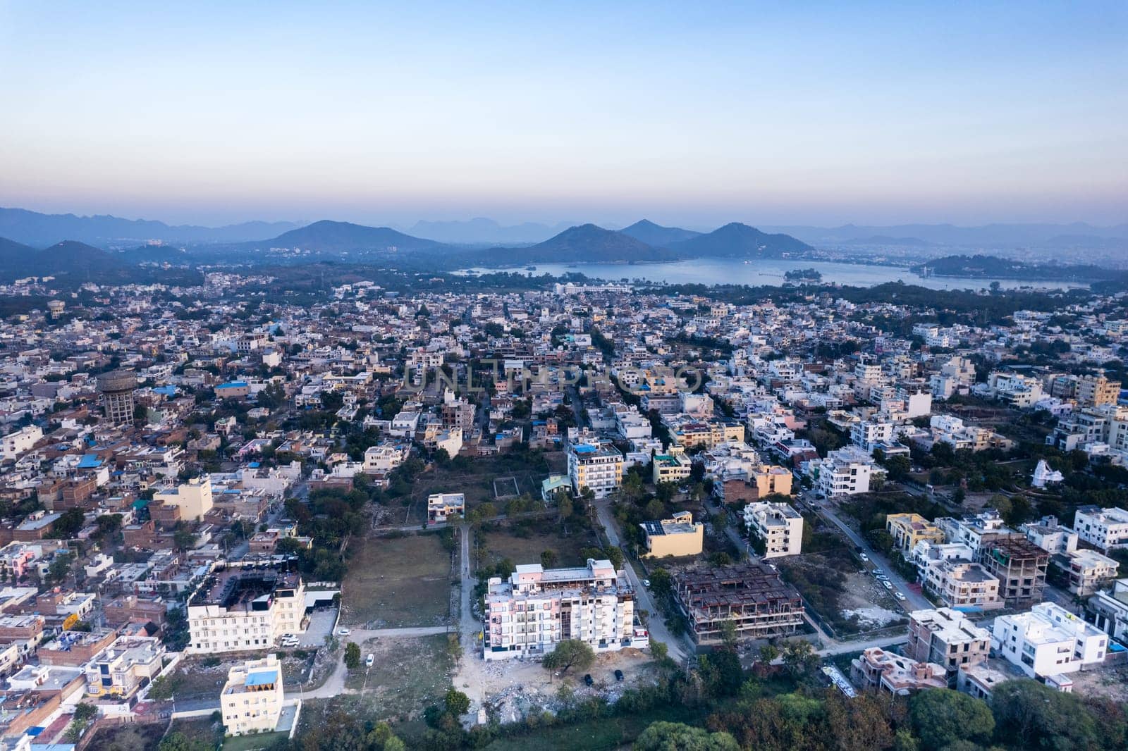 Aerial drone shot over udiapur, jaipur, kota,, cityscape with homes, houses, buildings and aravalli hills and lakes in the distance hidden in fog in India
