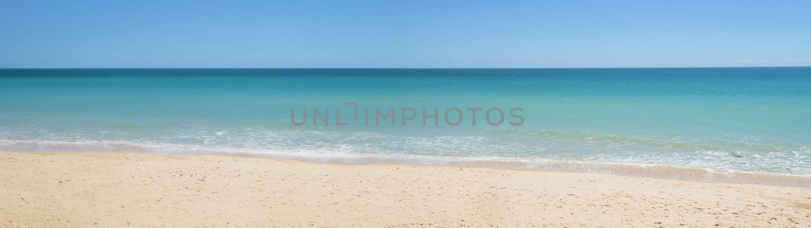 Soft blue ocean waves crashing on the sandy beach.