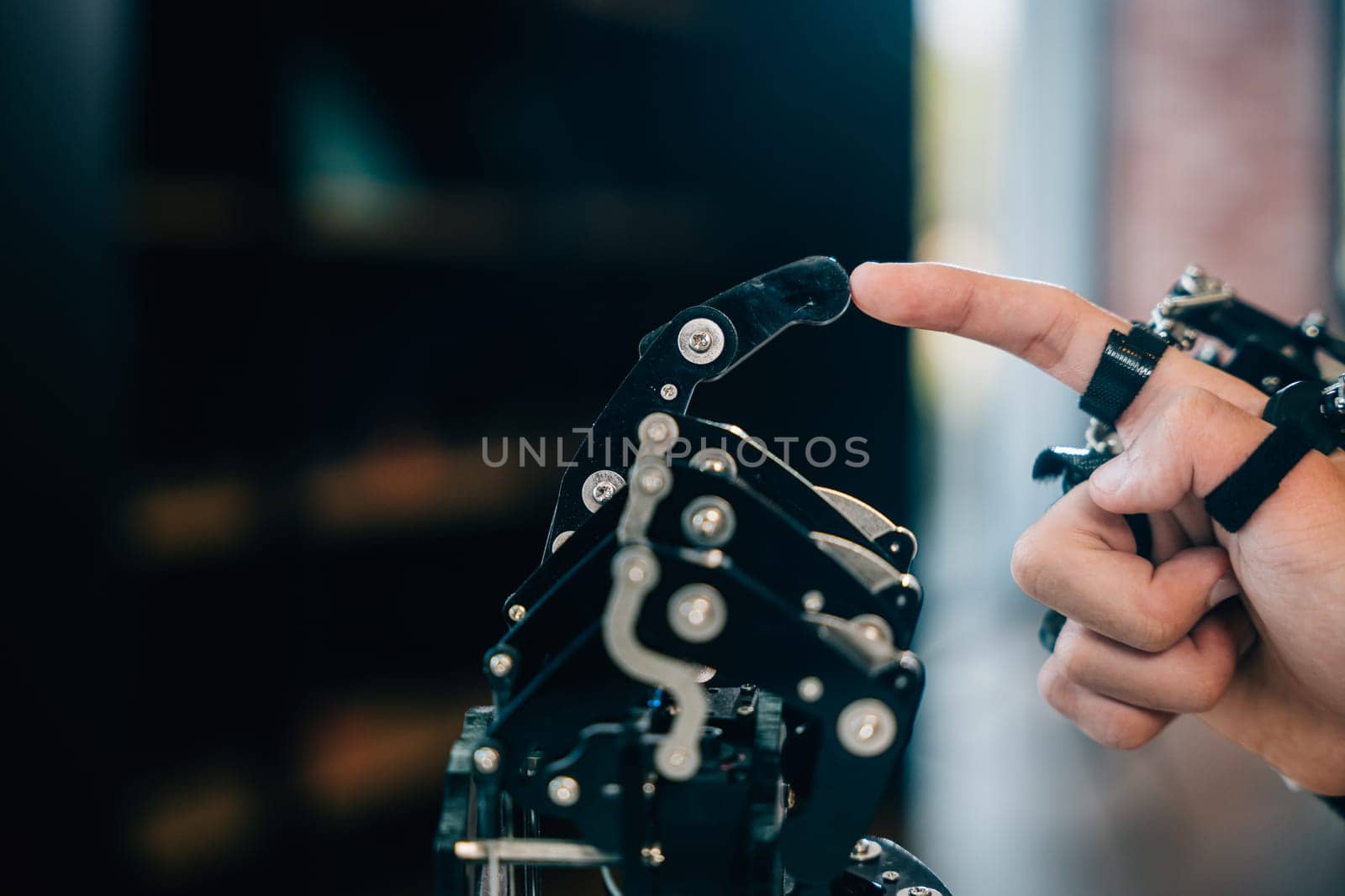 In a technical college a teenage boy tests a robot hand and arm touching fingers for educational skill development. Embracing futuristic AI and human connection in learning. by Sorapop