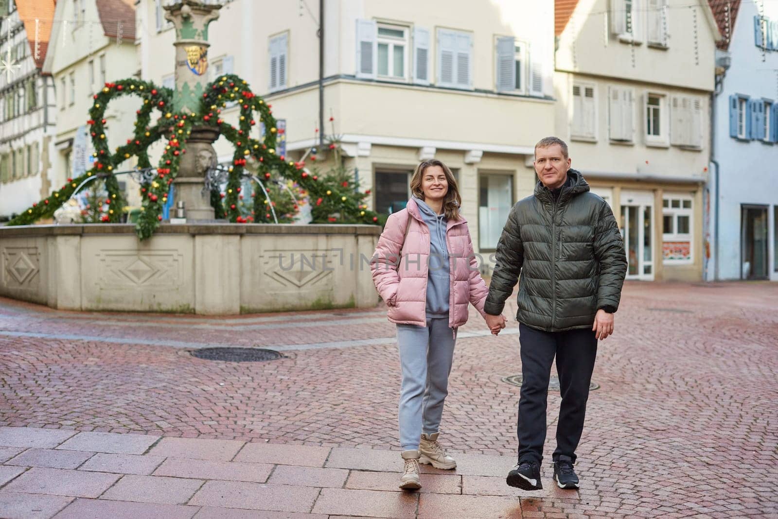 Loving couple of tourists walking around old town. Man woman couple walking europe old town Germany. Couple of lovers leisurely stroll in the cool autumn morning on the streets of a BIETIGHEIM-BISSINGEN (Germany). The guy holds his wife. Vacation, autumn, holiday. Couple Walking in Europe's Old Town