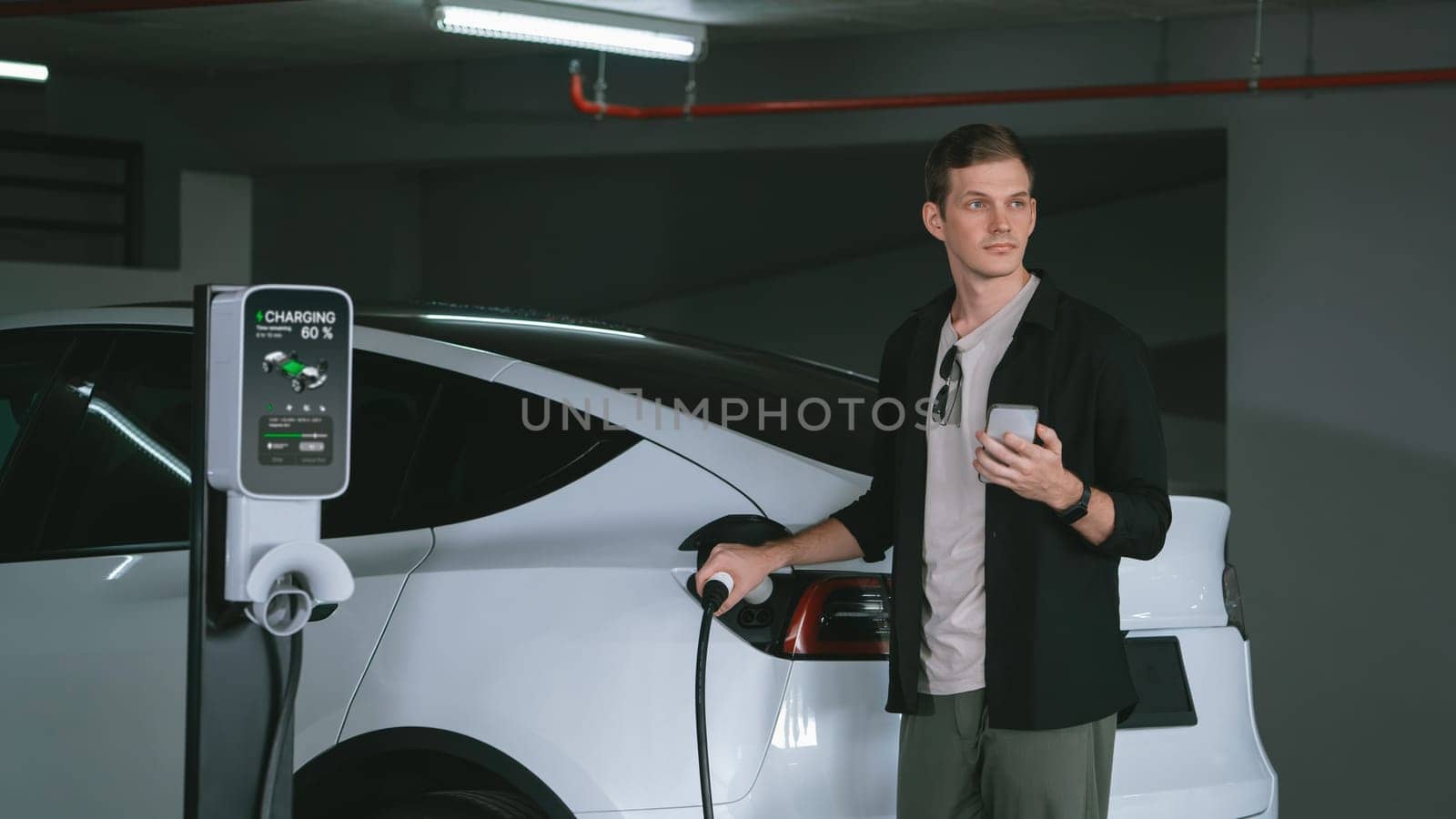 Young man travel with EV electric car to shopping center parking lot innards by biancoblue