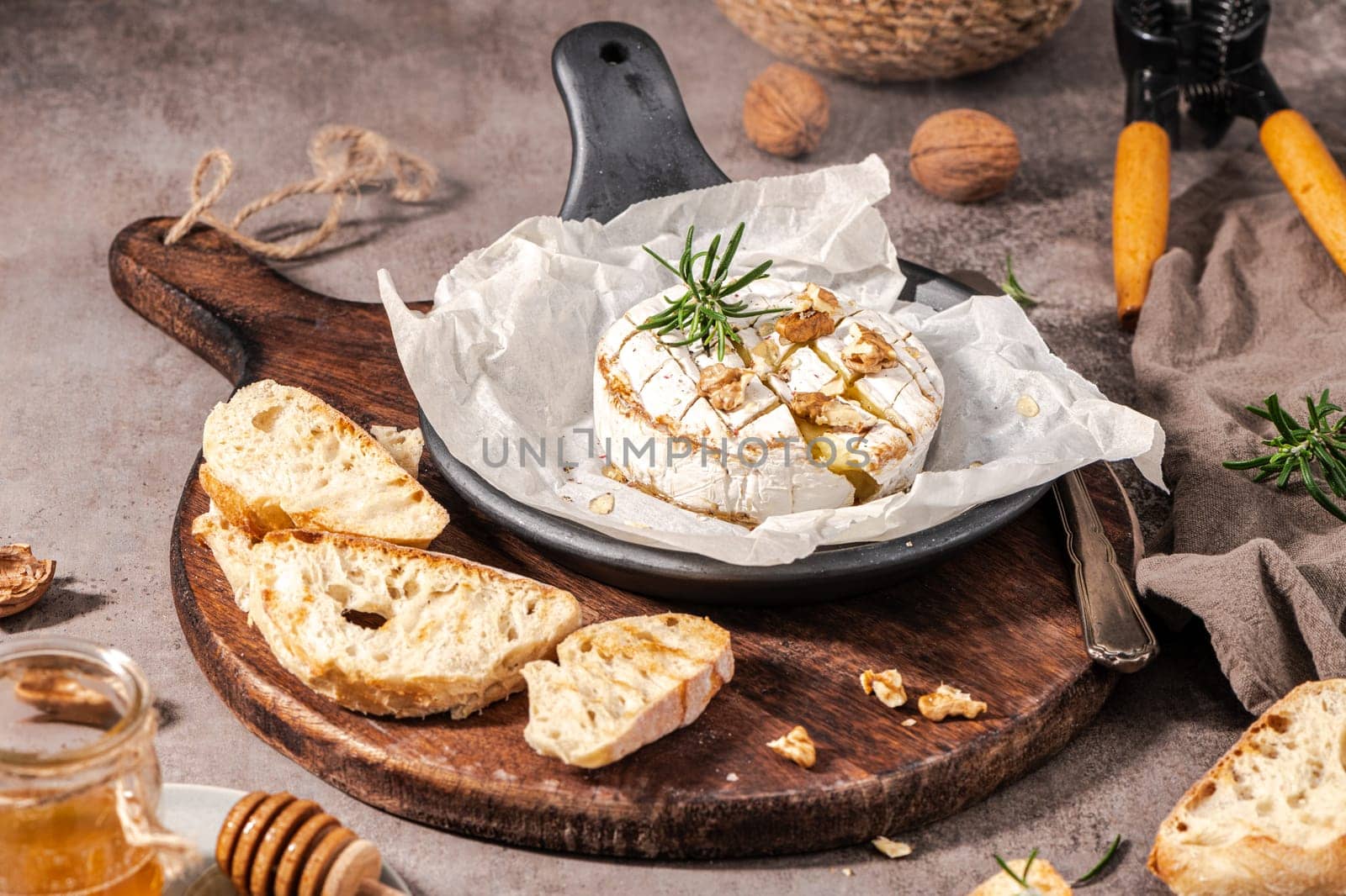 Brie type of cheese. Camembert cheese. Fresh sliced Brie cheese on a wooden tray with nuts, honey and leaves. Italian, French cheese.