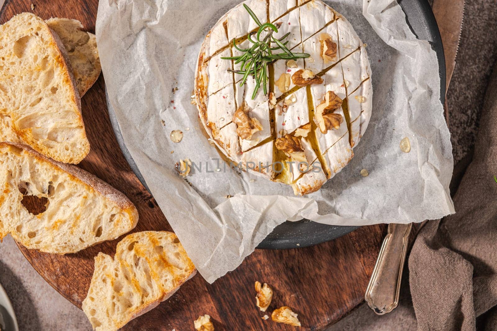 Brie type of cheese. Camembert cheese. Fresh sliced Brie cheese on a wooden tray with nuts, honey and leaves. Italian, French cheese.