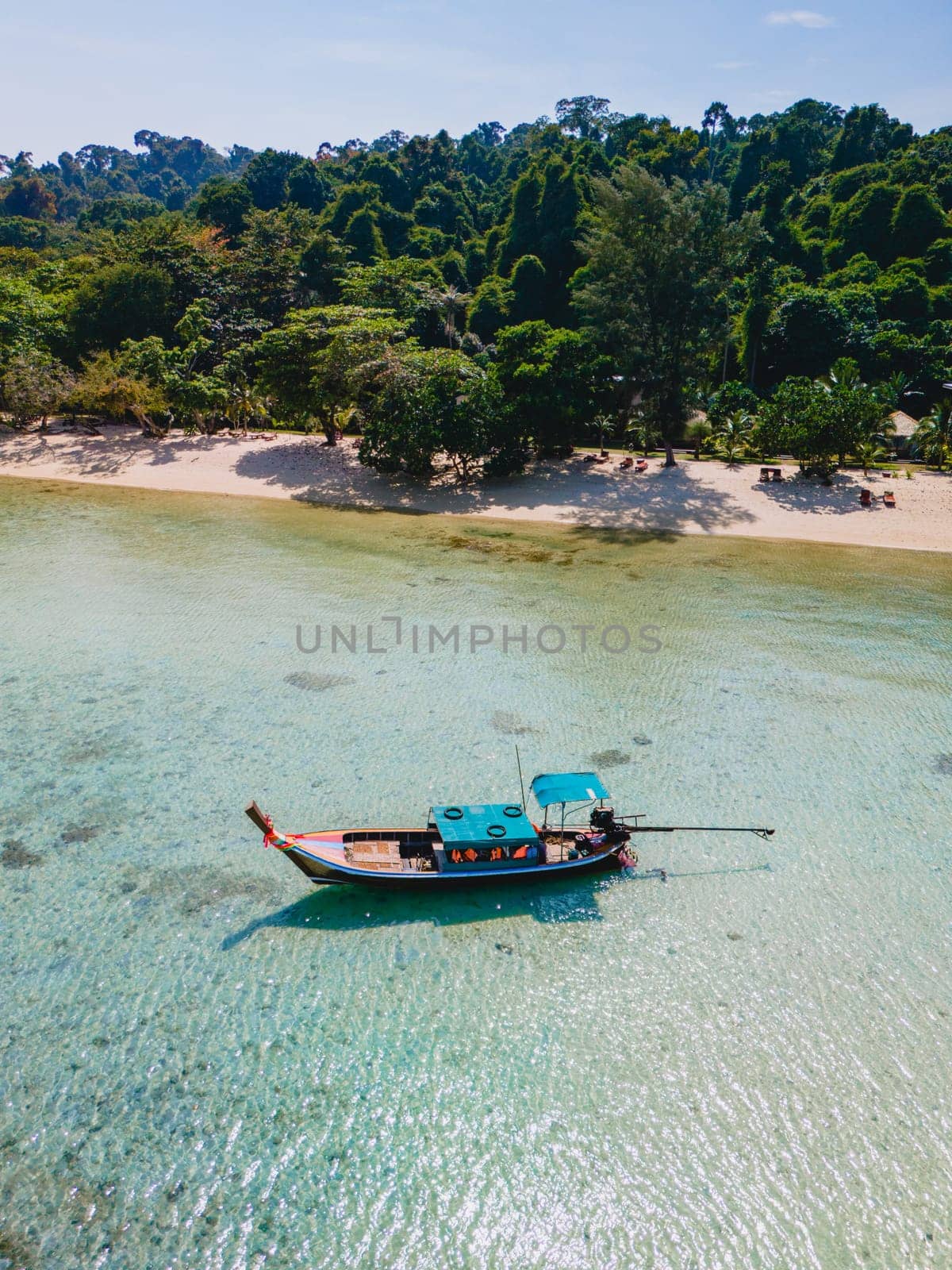 longtail boat in the turqouse colored ocean with clear water at Koh Kradan a tropical island in Trang Thailand, drone view from above