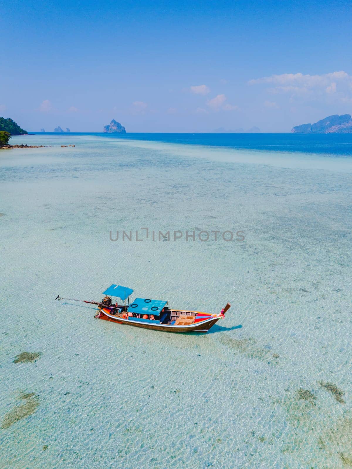 longtail boat in the turqouse colored ocean with clear water at Koh Kradan Thailand by fokkebok