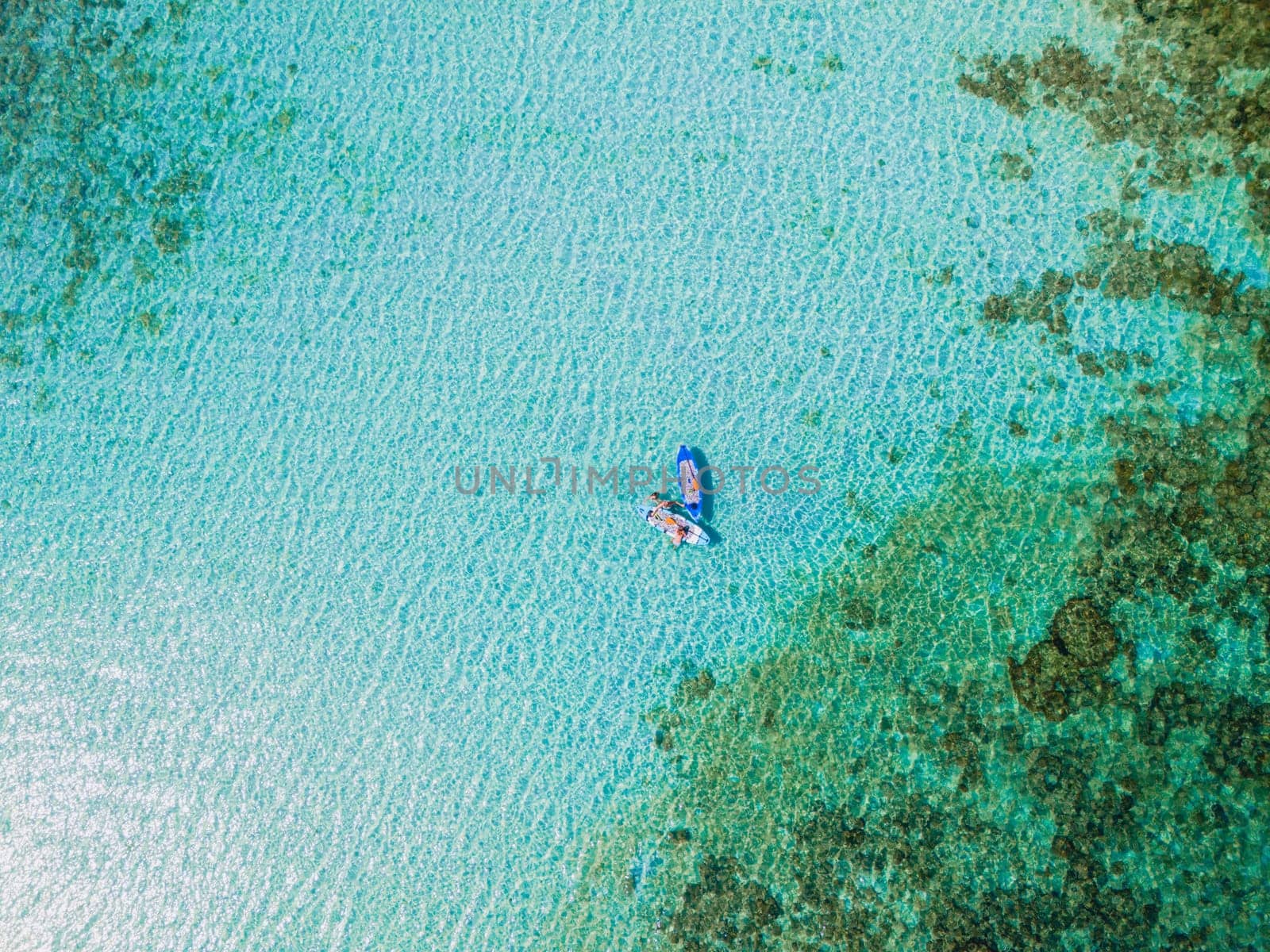 Asian woman at peddle board sup at Koh Kradan a tropical island in Thailand, Top down view picture of a woman paddling on the sup board.