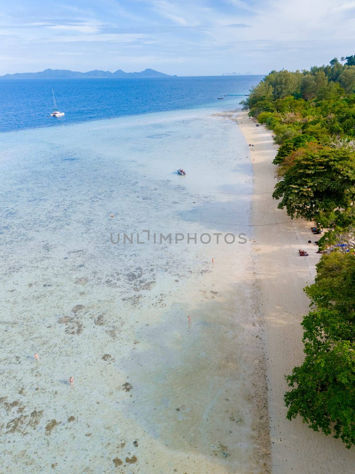 aerial view at Koh Kradan a tropical island with palm trees soft white sand, and a turqouse colored ocean in Koh Kradan Trang Thailand at sunset