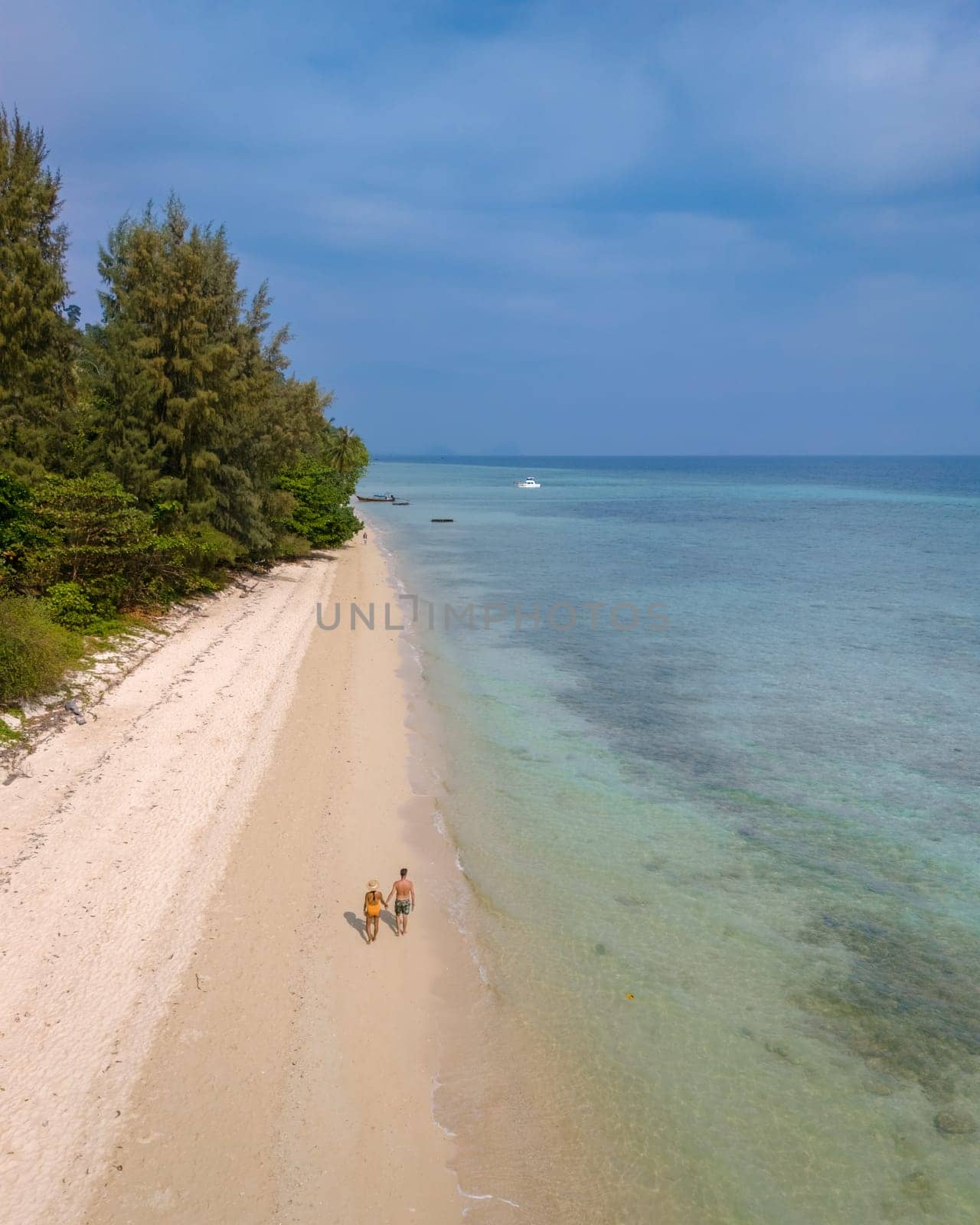 Drone aerial view at Koh Ngai island with palm trees and soft white sand, and a turqouse colored ocean in Koh Ngai Trang Thailand