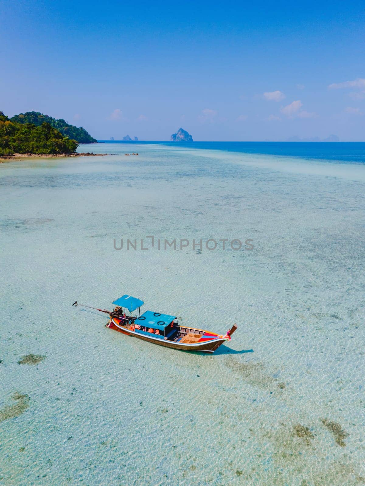 top view at a longtail boat in the turqouse colored ocean with clear water at Koh Kradan a tropical island in Trang Thailand
