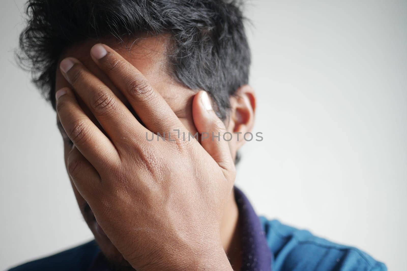 Close up of sad man covering face with hand
