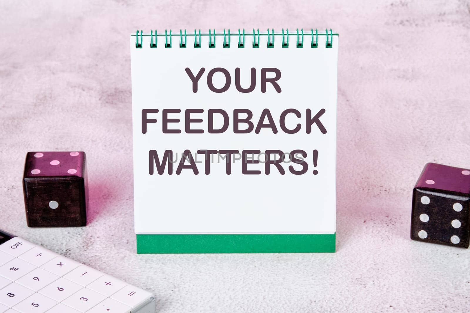 YOUR FEEDBACK MATTERS text on a white notepad sheet next to dice on an abstract background