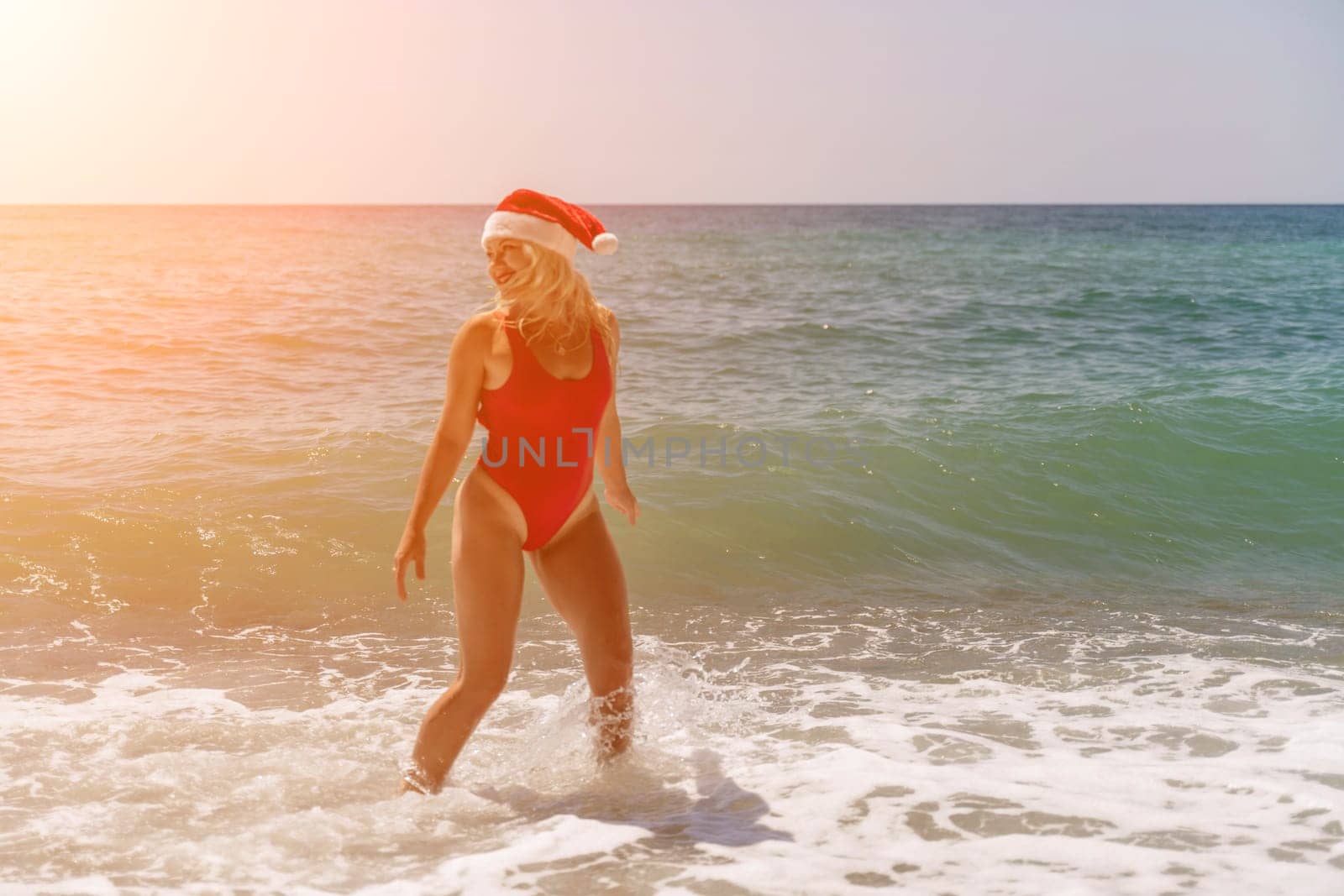 A woman in Santa hat on the seashore, dressed in a red swimsuit. New Year's celebration in a hot country by Matiunina