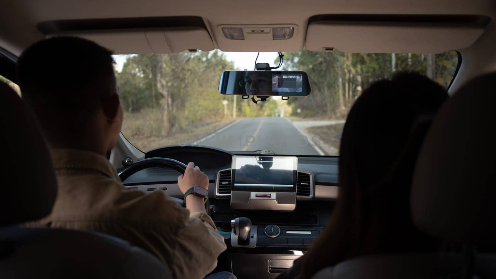 Rear view shot of young couple driving on country road. Traveling and vacation concept by prathanchorruangsak