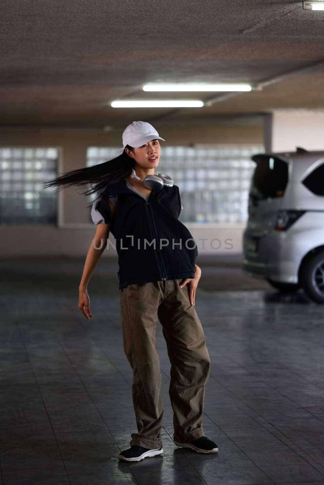 Young woman performing hip-hop dance in parking garage. Hobby and active lifestyle concept.