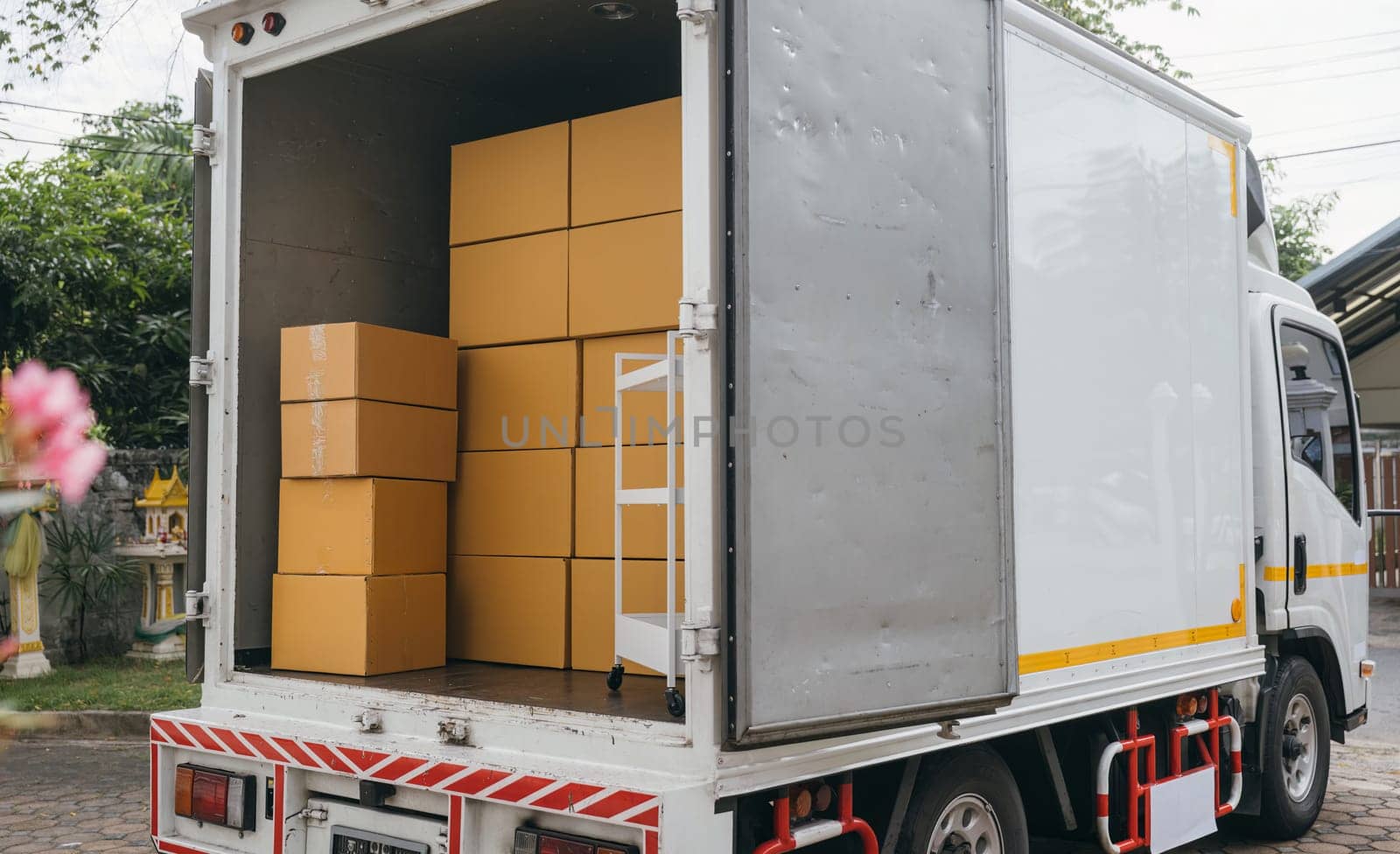 Outdoor scene, White delivery van and open car trunk carrying cardboard boxes. Logistic service for transporting items. House relocation. Moving Day Concept. by Sorapop
