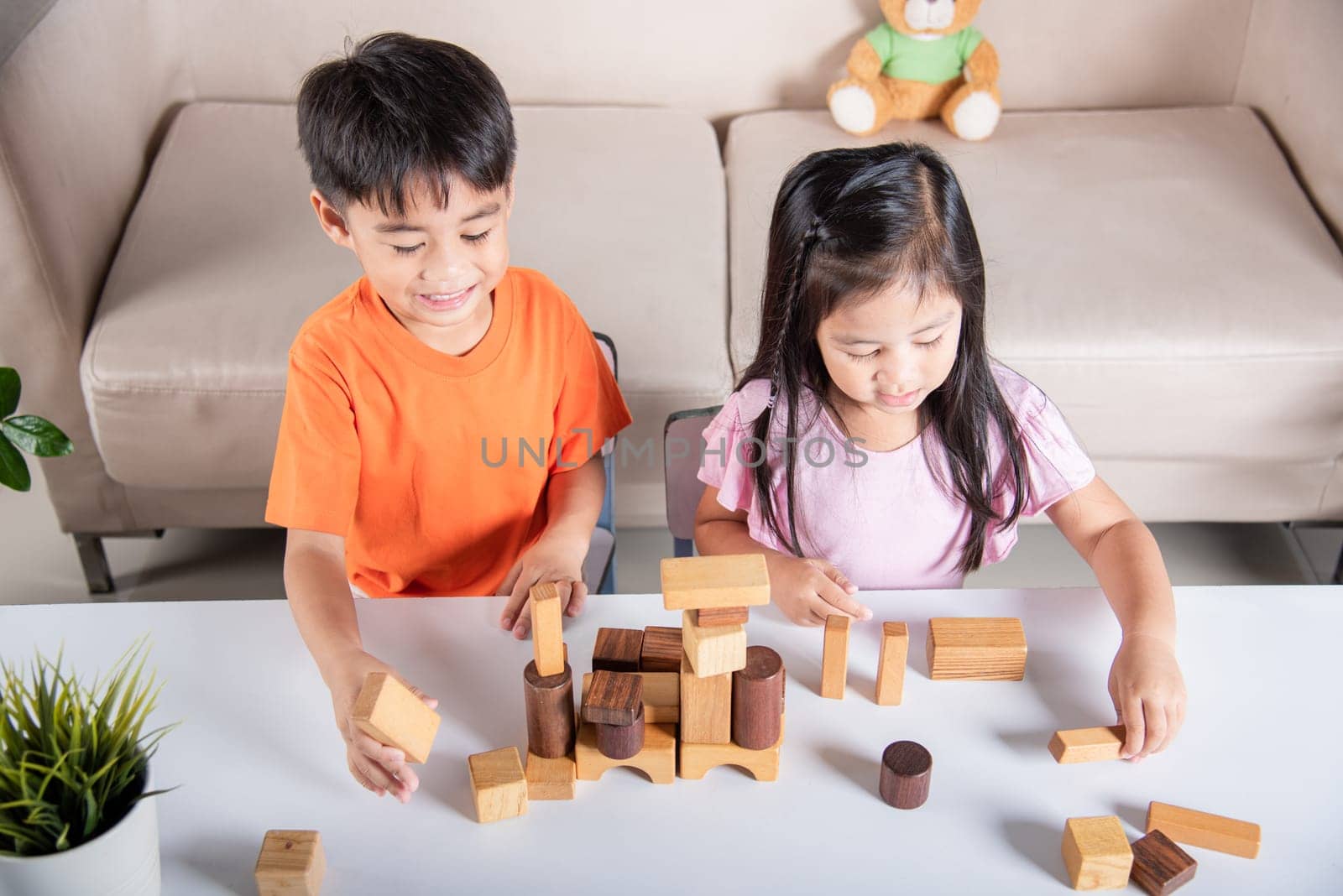 Children boy and girl playing with constructor wooden block building by Sorapop