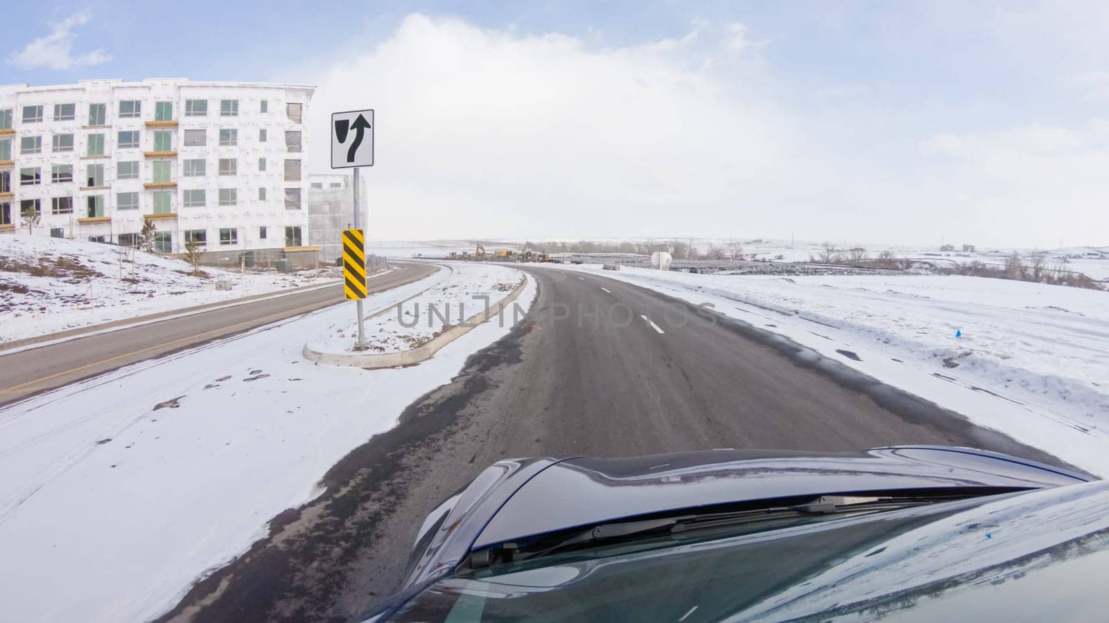 Centennial, Colorado, USA-January 30, 2023-Navigating a frontage road post-winter storm offers a serene drive. The surrounding landscape, blanketed in snow, contributes to the peaceful and picturesque environment, enhancing the driving experience.