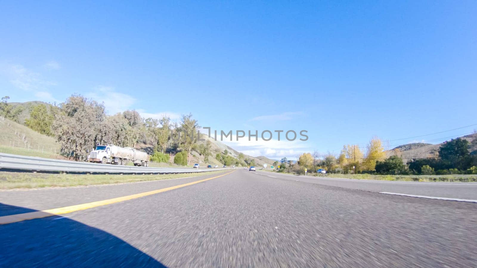 Santa Maria, California, USA-December 6, 2022-On a crisp winter day, a car cruises along the iconic Highway 1 near San Luis Obispo, California. The surrounding landscape is brownish and subdued, with rolling hills and patches of coastal vegetation flanking the winding road.