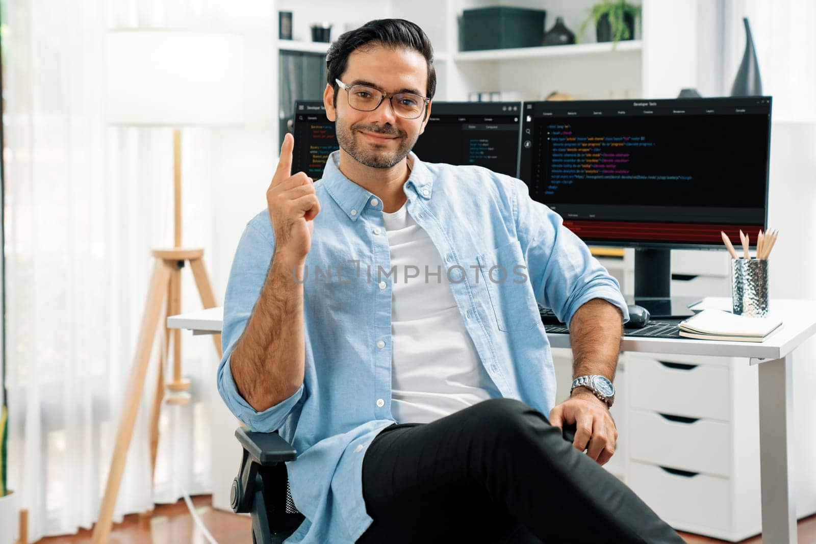 Profile's smart IT developer looking camera to pose wearing glasses against on software development coding on two pc screen, presenting program update online website data at modern office. Surmise.