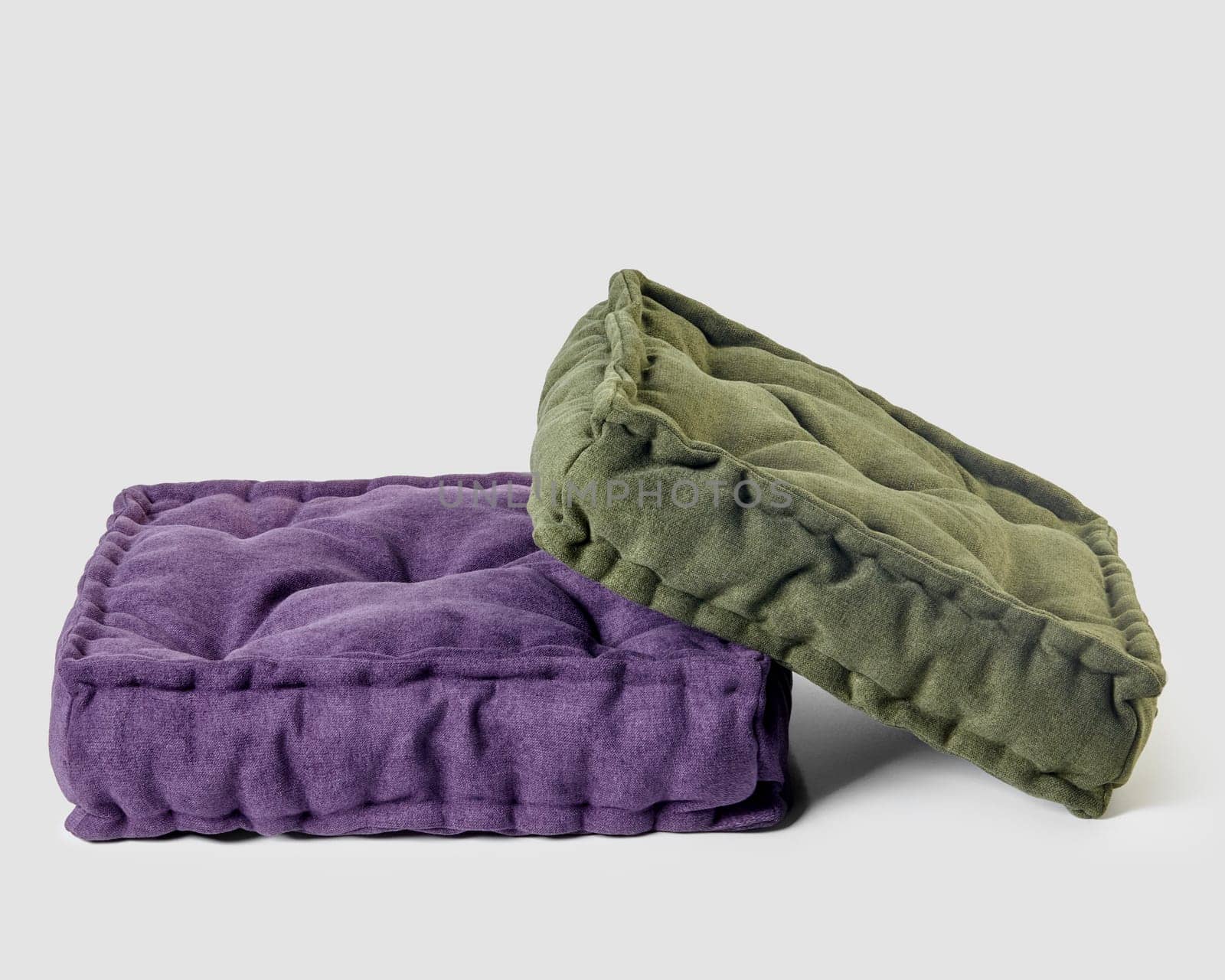 Two plush linen floor cushions in complementary purple and green shades on white background, offering blend of functional comfort and stylish home decor. Handmade furnishing accessories