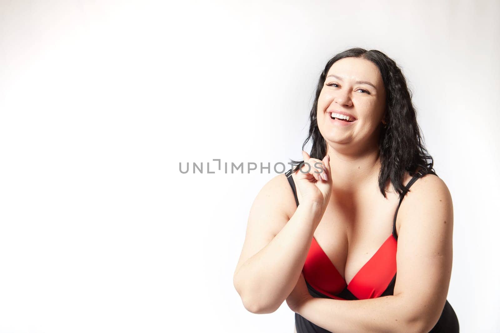 Portrait of attractive dreamy thick woman in red black swimsuit posing on white background. Body positive, photoshoot, selfie. Funny plus size model