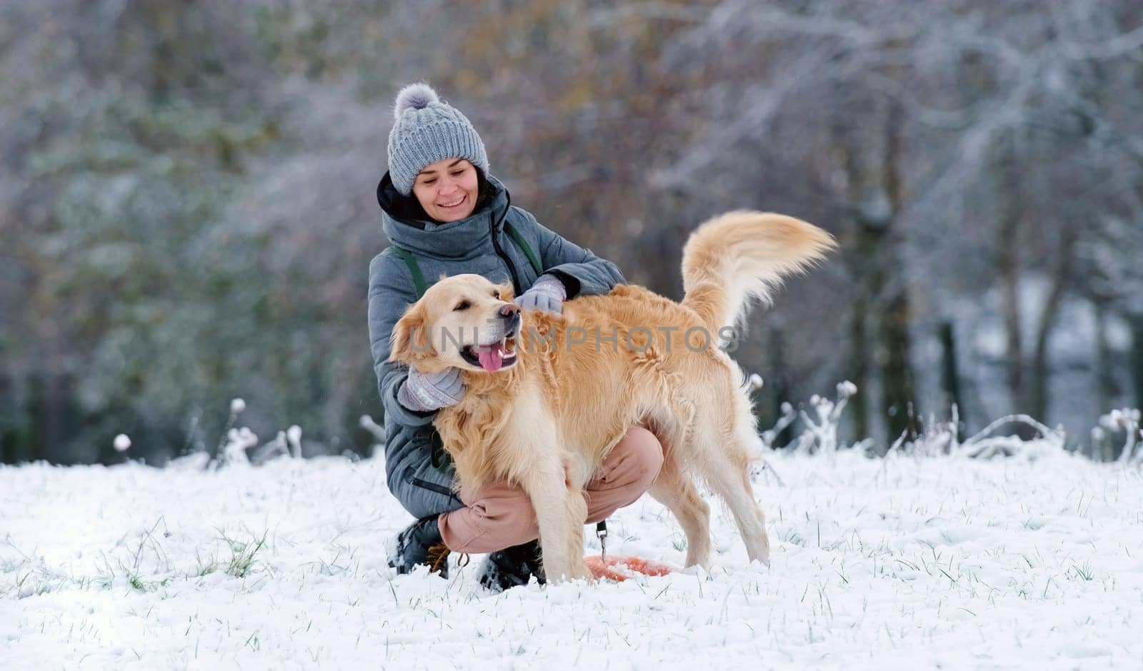 Woman Petting Her Adorable Golden Retriever Dog On A Snow Field In Winter