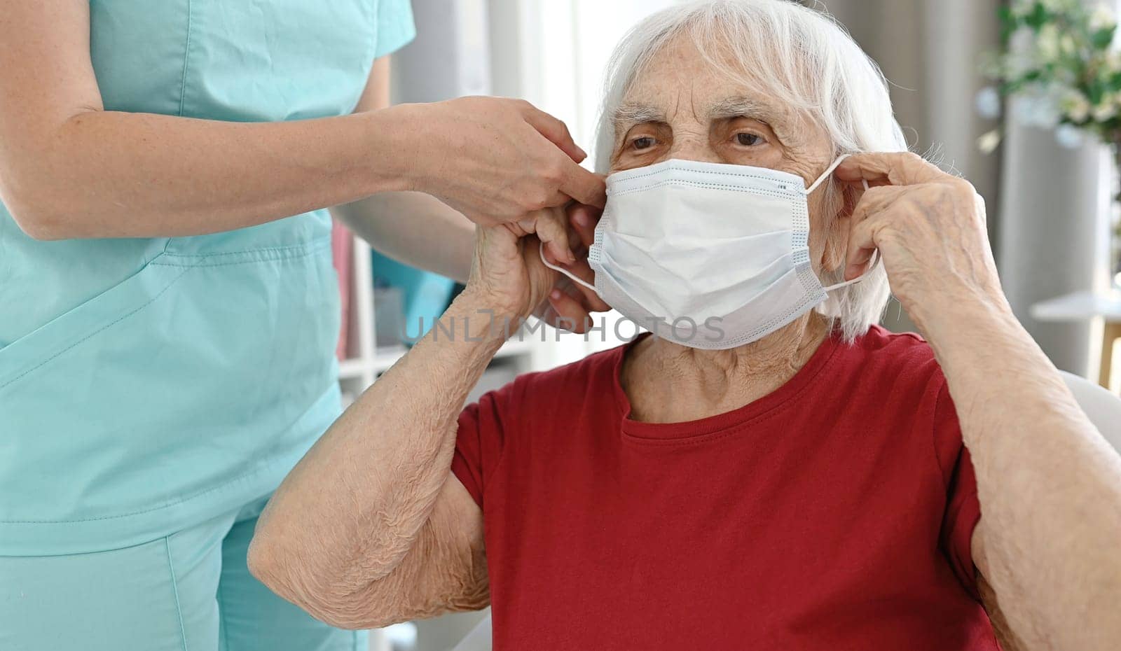 Nurse Helps Elderly Woman Put On Medical Protective Mask During Period Of Viral And Respiratory Diseases
