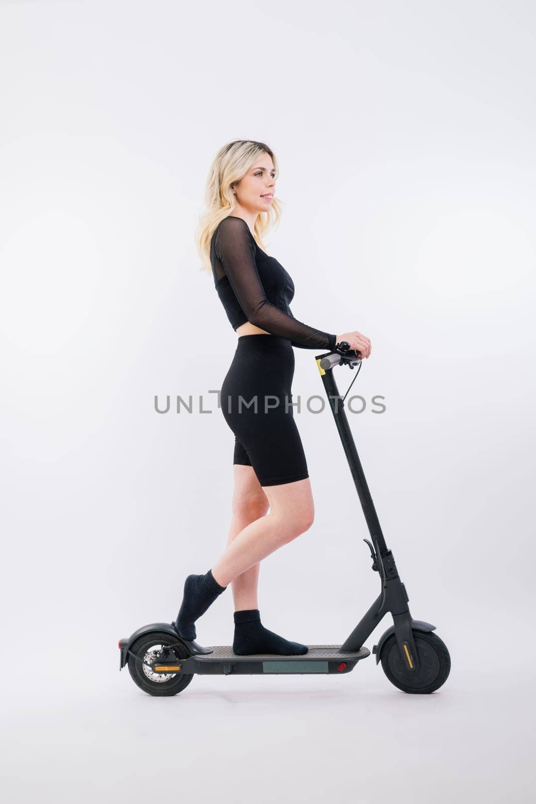 A blonde woman on a red background sitting on electro scooter and resting, copy space