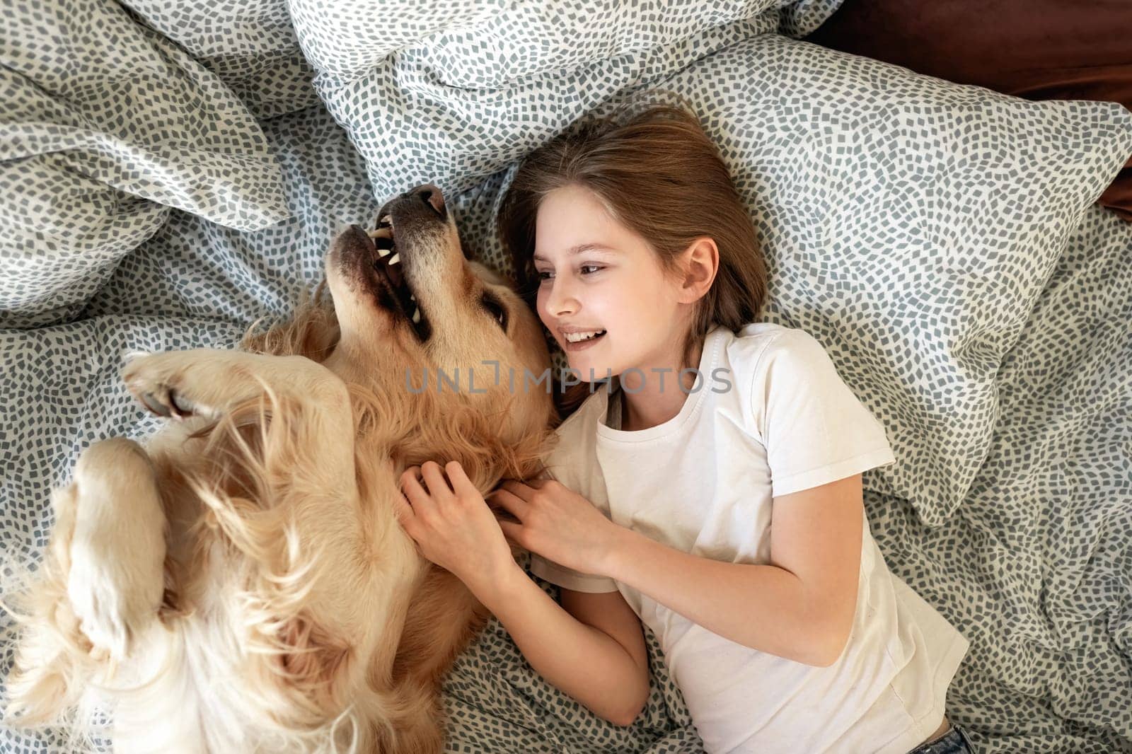 Cute Little Girl Playing With Golden Retriever Dog In Bed