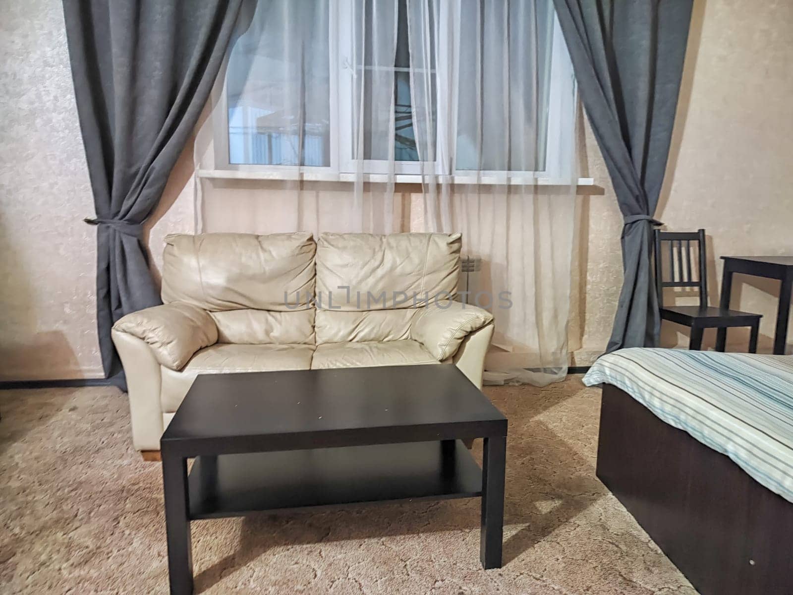 Stylish bedroom in beige tones and colors with double bed, sofa, table. Concept of cozy bedroom, living room or hotel room