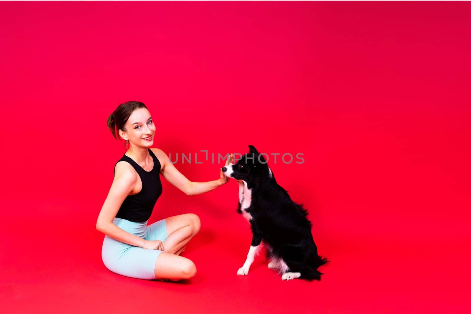 Beautiful sport female with border collie in a studio